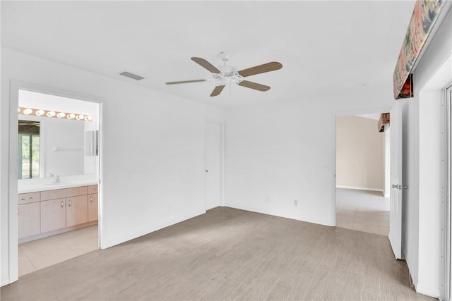 unfurnished bedroom featuring connected bathroom, sink, ceiling fan, and light wood-type flooring