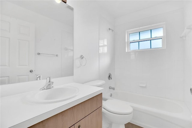 full bathroom featuring tiled shower / bath, vanity, and toilet