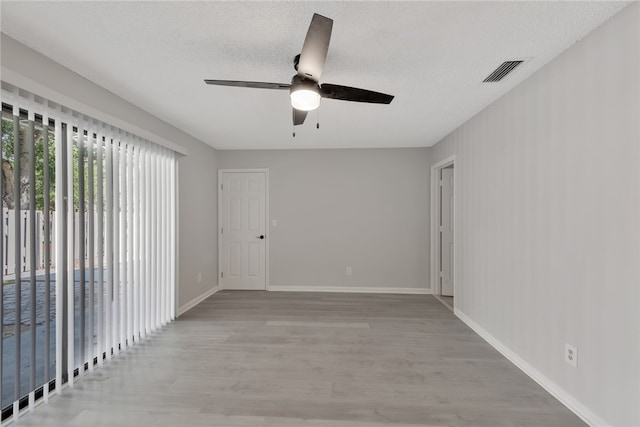 spare room featuring light hardwood / wood-style floors, ceiling fan, and a textured ceiling