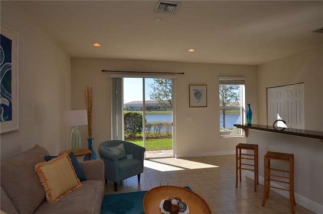 tiled living room featuring a wealth of natural light and a water view