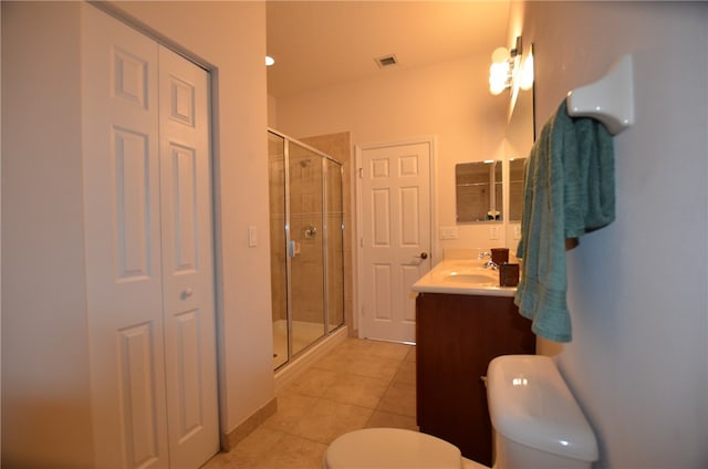 bathroom featuring tile patterned flooring, vanity, toilet, and a shower with door