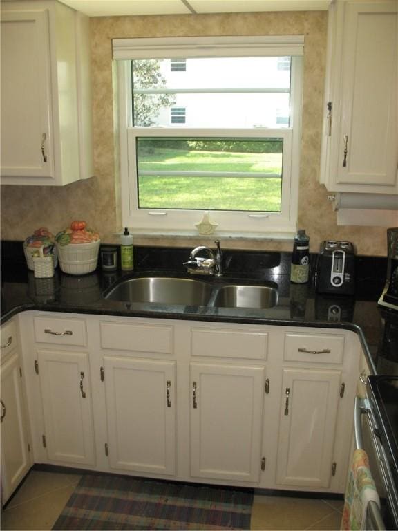 kitchen featuring sink, white cabinets, and dark tile patterned flooring