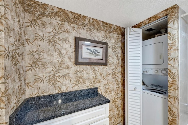 1480 Ocean Dr Unit 4C, Vero Beach, FL 32963 - laundry area featuring wallpapered walls, estacked washer and dryer, and a textured ceiling