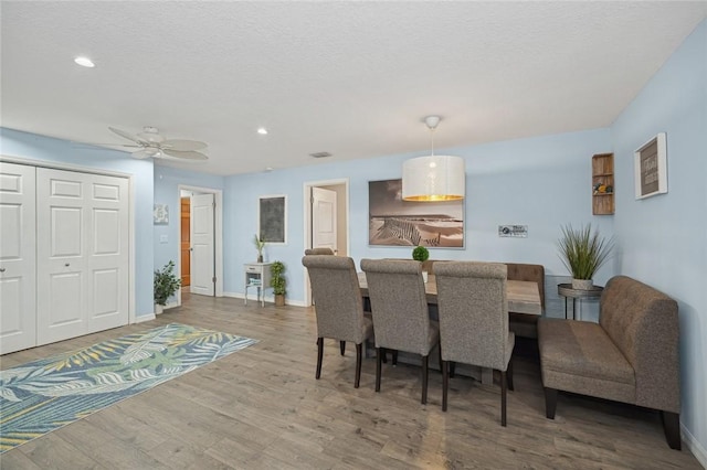 dining room with a textured ceiling, ceiling fan, and hardwood / wood-style flooring