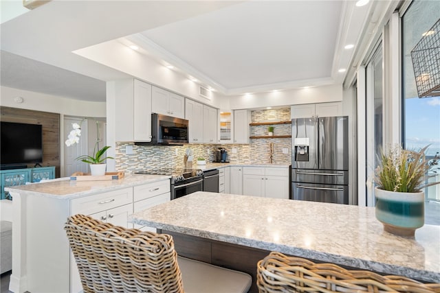 kitchen featuring white cabinetry, kitchen peninsula, stainless steel appliances, and ornamental molding