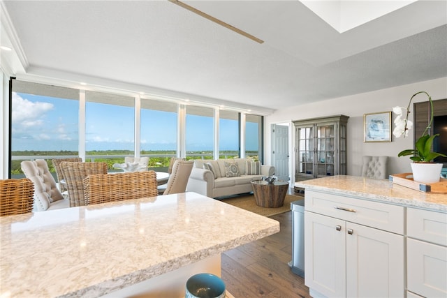 kitchen featuring dark wood-type flooring, white cabinetry, a textured ceiling, and expansive windows