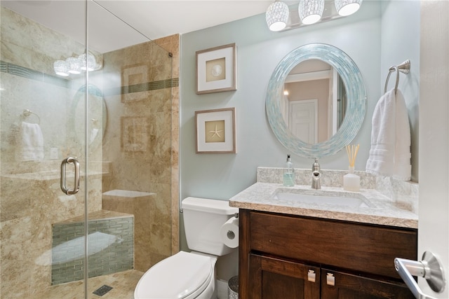 bathroom featuring a shower with door, vanity, and toilet