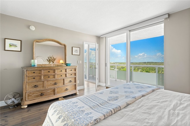 bedroom with hardwood / wood-style flooring, a textured ceiling, and access to outside