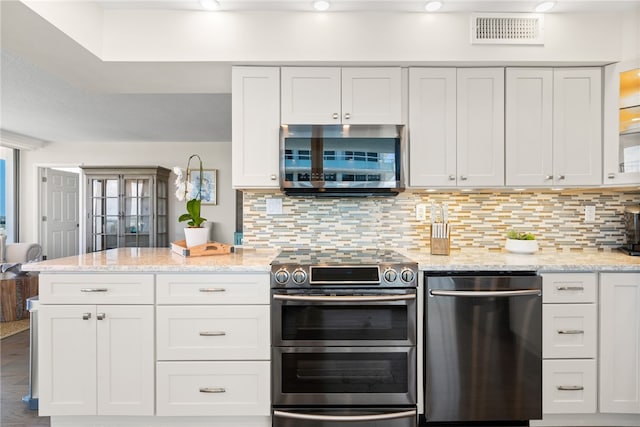 kitchen with white cabinetry, appliances with stainless steel finishes, tasteful backsplash, and light stone countertops