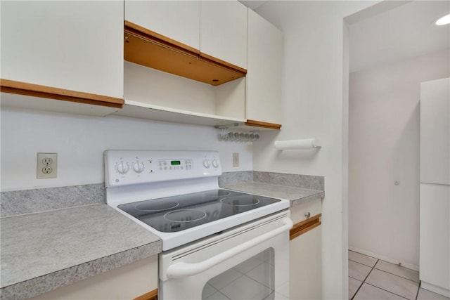 kitchen with white range with electric cooktop, light tile patterned floors, and white cabinets