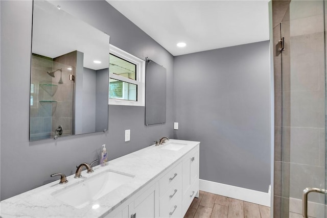 bathroom featuring wood-type flooring, a shower with shower door, and vanity