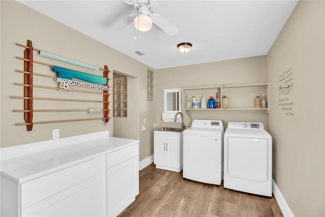 laundry room with sink, ceiling fan, cabinets, washer and dryer, and light wood-type flooring