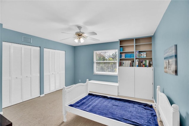 unfurnished bedroom featuring carpet flooring, two closets, and ceiling fan