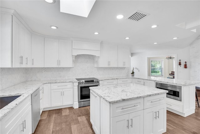 kitchen with a kitchen island, appliances with stainless steel finishes, white cabinets, and kitchen peninsula