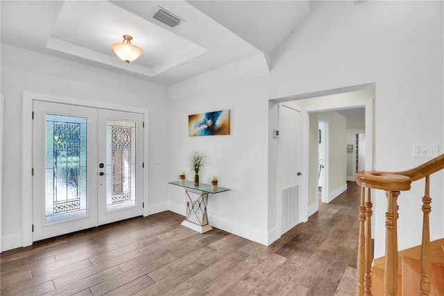 foyer featuring a raised ceiling, hardwood / wood-style flooring, and french doors