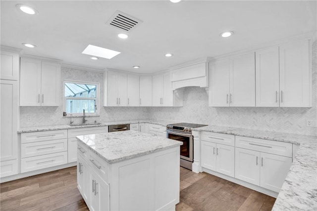 kitchen with sink, hardwood / wood-style flooring, stainless steel appliances, light stone counters, and white cabinets