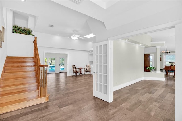 interior space featuring hardwood / wood-style flooring, a skylight, ceiling fan with notable chandelier, and french doors