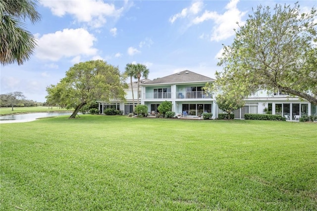 exterior space featuring a water view, a balcony, and a lawn