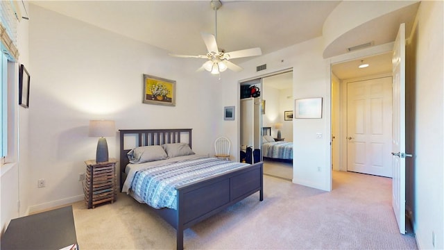 bedroom featuring light colored carpet, ceiling fan, and a closet