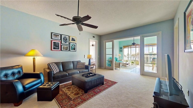 carpeted living room featuring ceiling fan and a textured ceiling