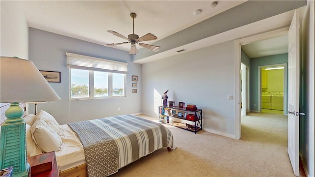 bedroom featuring washer and dryer, light colored carpet, and ceiling fan