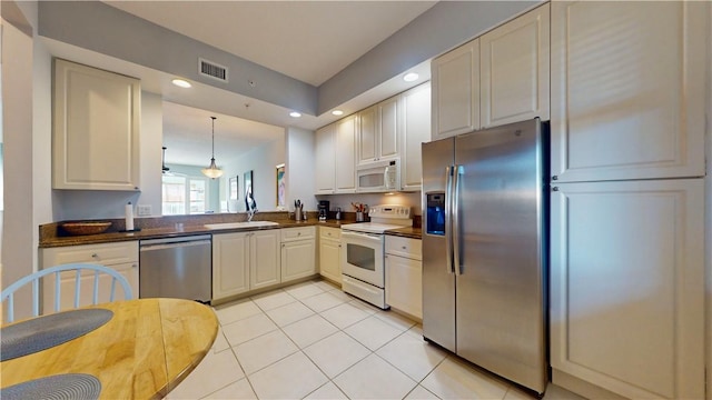 kitchen featuring stainless steel appliances, sink, light tile patterned floors, and decorative light fixtures