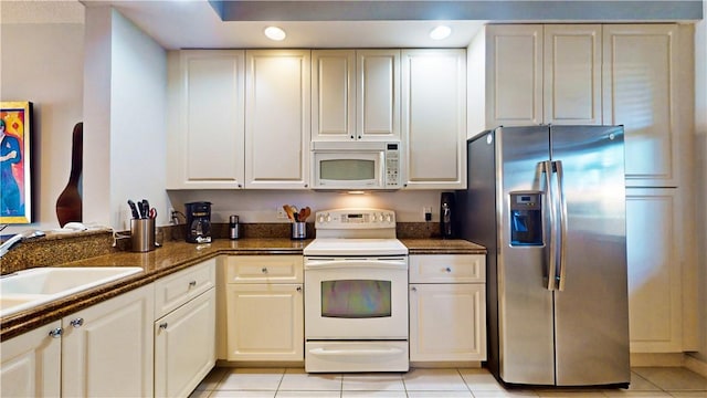 kitchen featuring light tile patterned flooring, white appliances, sink, and white cabinets