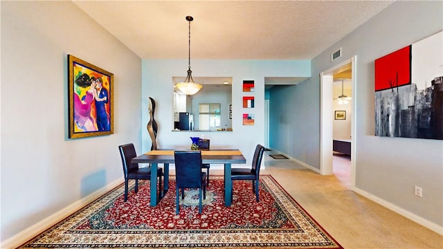 carpeted dining room with a textured ceiling