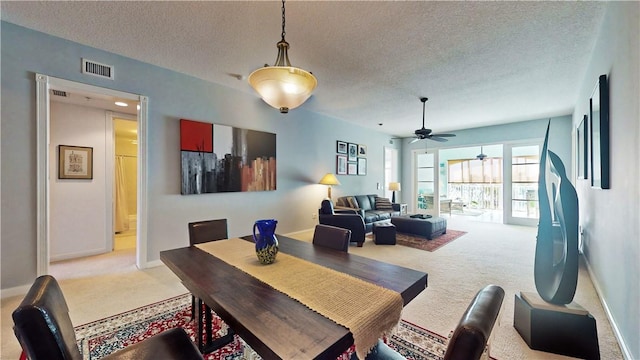 carpeted dining room featuring ceiling fan and a textured ceiling