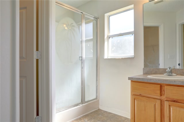 bathroom featuring a shower with door, vanity, and tile patterned flooring