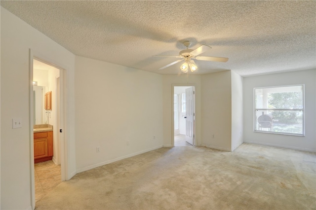 spare room with a textured ceiling, light colored carpet, and ceiling fan