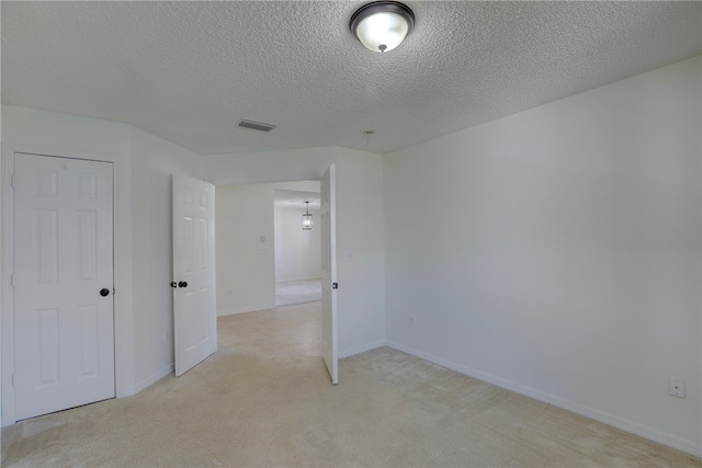 unfurnished bedroom with a closet, a textured ceiling, and light colored carpet