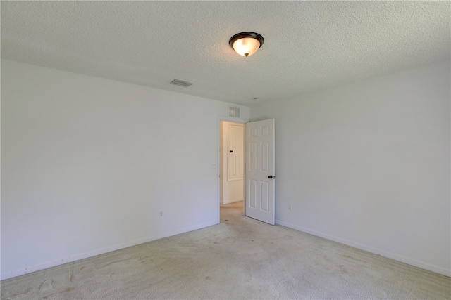 spare room featuring a textured ceiling and light carpet