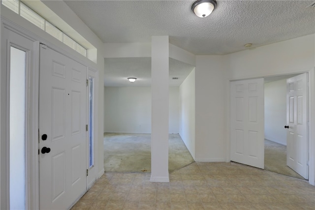 carpeted foyer with a textured ceiling