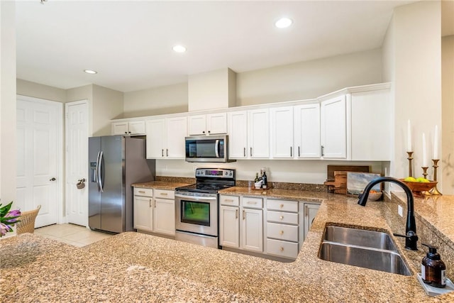 kitchen with light stone countertops, sink, light tile patterned flooring, white cabinets, and appliances with stainless steel finishes