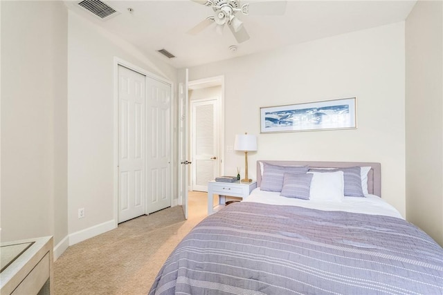 bedroom with ceiling fan, light colored carpet, and a closet