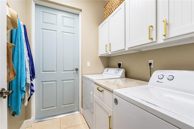 laundry room featuring cabinets, light tile patterned floors, and washing machine and dryer