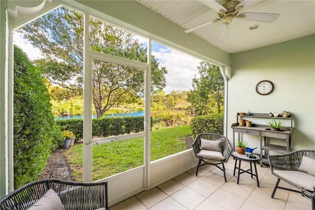 sunroom / solarium with ceiling fan and a water view