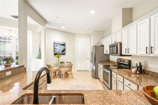 kitchen featuring white cabinetry, sink, an inviting chandelier, light stone counters, and appliances with stainless steel finishes