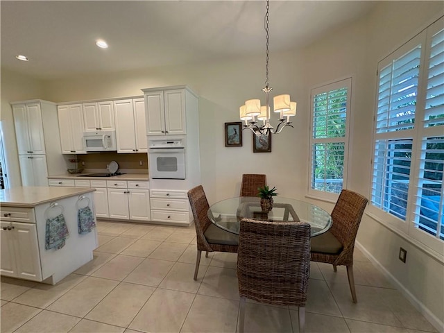 dining space featuring light tile patterned floors, recessed lighting, an inviting chandelier, and baseboards