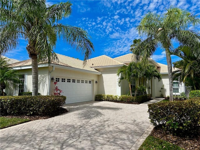 view of front of house with a tile roof, an attached garage, driveway, and stucco siding