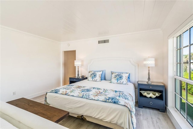 bedroom featuring visible vents, ornamental molding, wood finished floors, and multiple windows