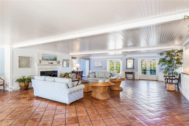 living area with a fireplace, beam ceiling, and french doors