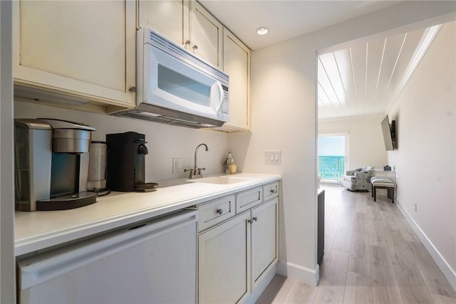 kitchen featuring light countertops, a sink, baseboards, and white appliances