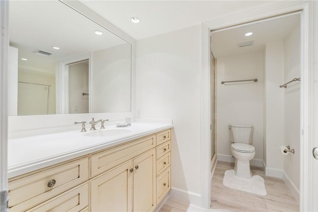 bathroom featuring vanity, toilet, a stall shower, visible vents, and baseboards