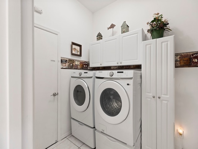 laundry room with washer and clothes dryer, cabinets, and light tile patterned floors