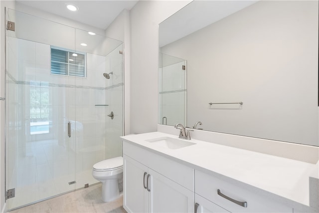 bathroom featuring vanity, toilet, and a shower with shower door