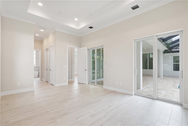 unfurnished room with a raised ceiling and light wood-type flooring