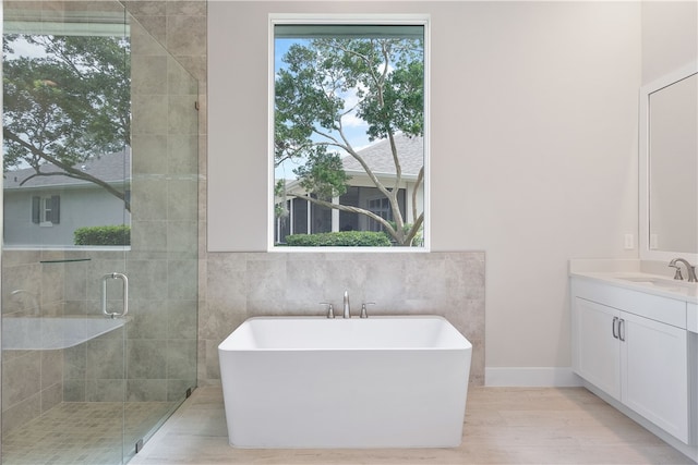 bathroom featuring vanity, hardwood / wood-style flooring, separate shower and tub, and tile walls