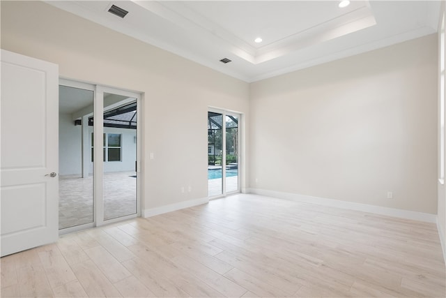 unfurnished room featuring a raised ceiling, light hardwood / wood-style flooring, and crown molding